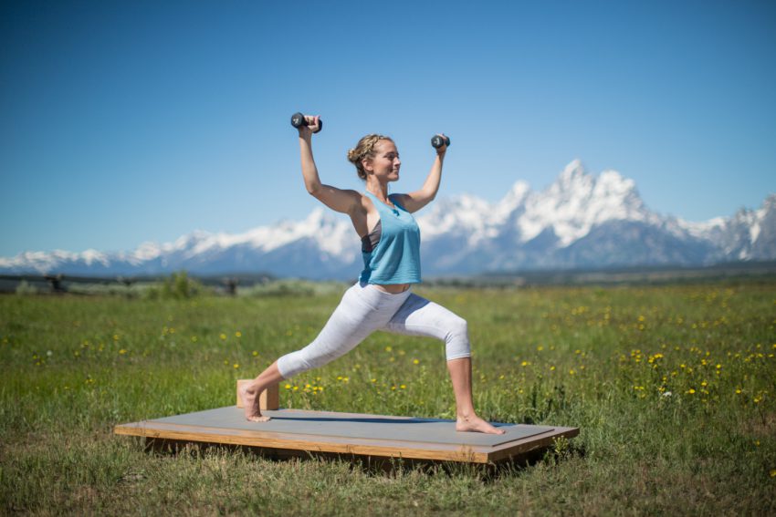 woman practices lunge pose with weights