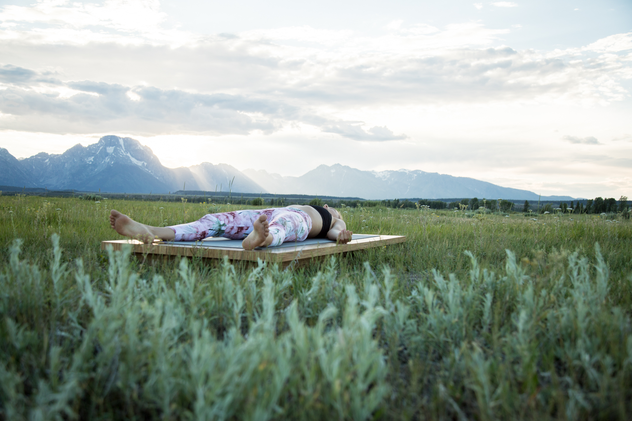 woman lies in savasana yoga pose outdoors
