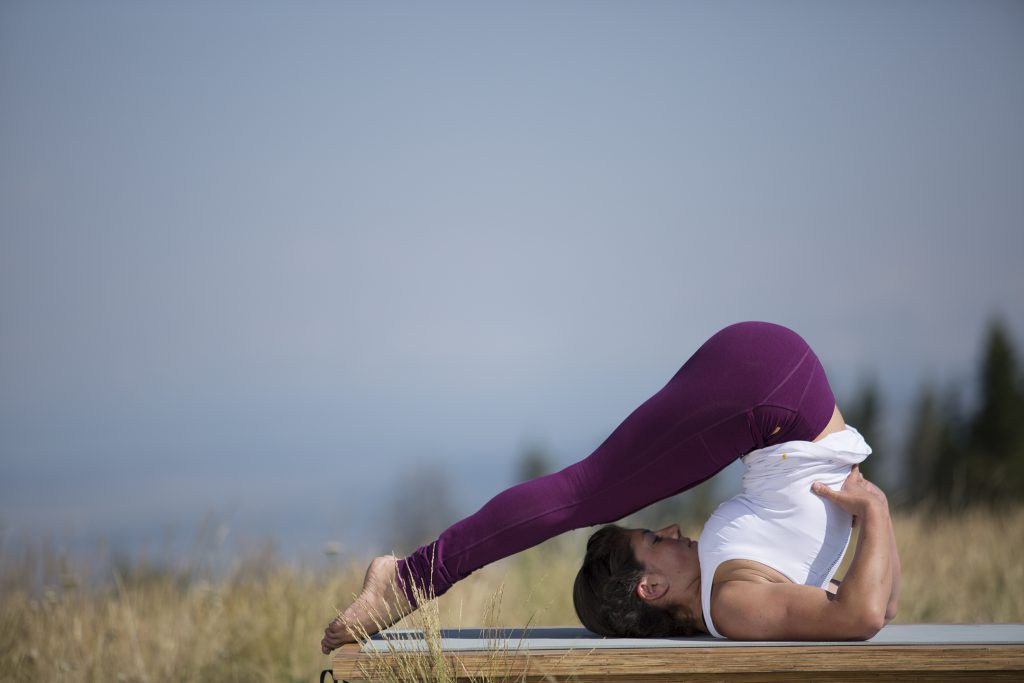woman practices plow pose to relieve stress - YogaToday