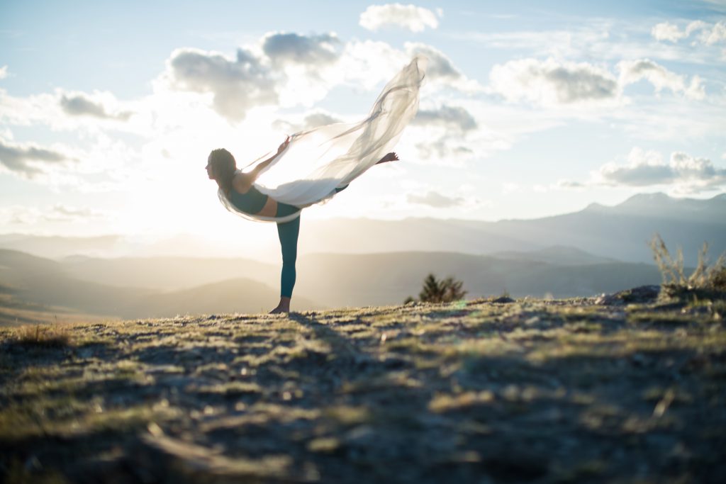 woman practices intentional yoga at sunset with draped white scarf -yogatoday