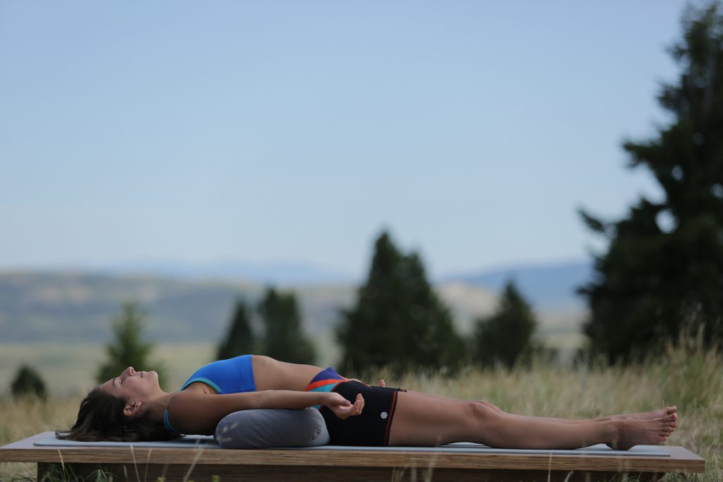 woman practices savasana at the end of yoga class - yogatoday
