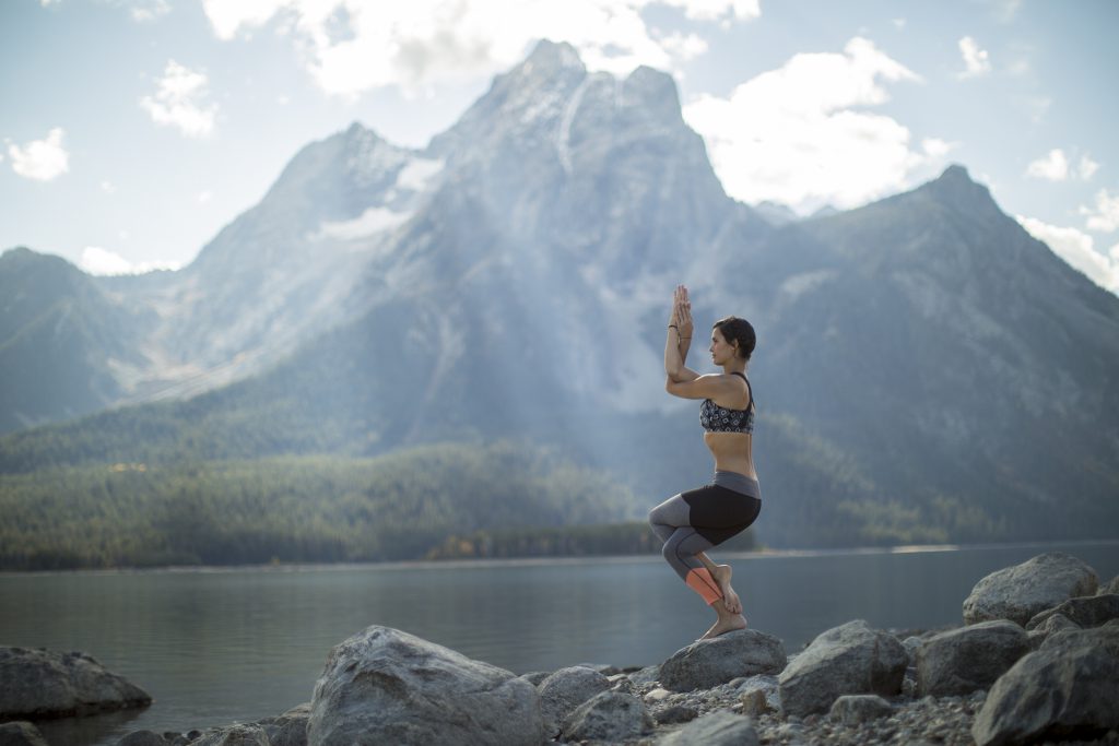 woman practices eagle pose in Grand Teton National Park -yogatoday