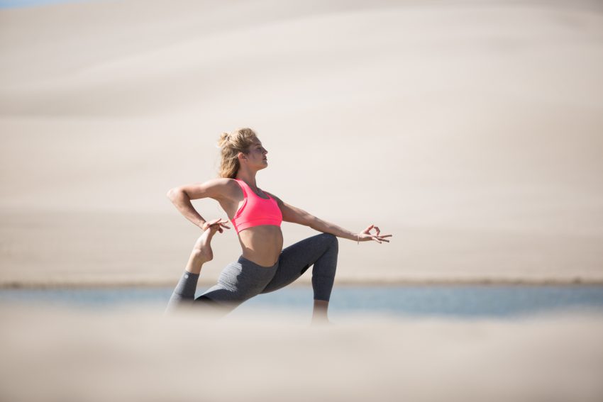 woman practices yoga in sand dunes